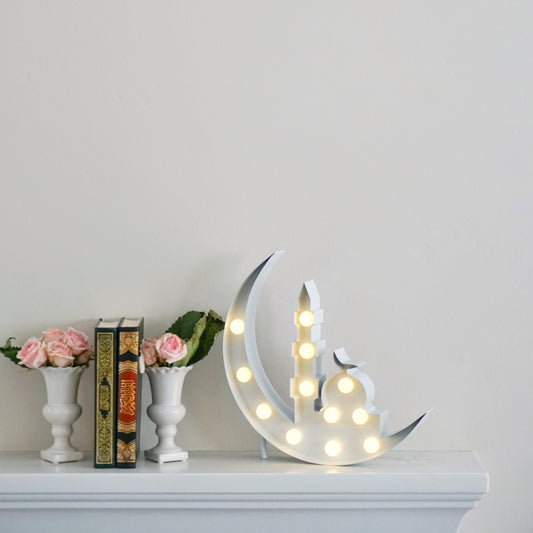 Crescent marquee next to qurans and flowers on a shelf