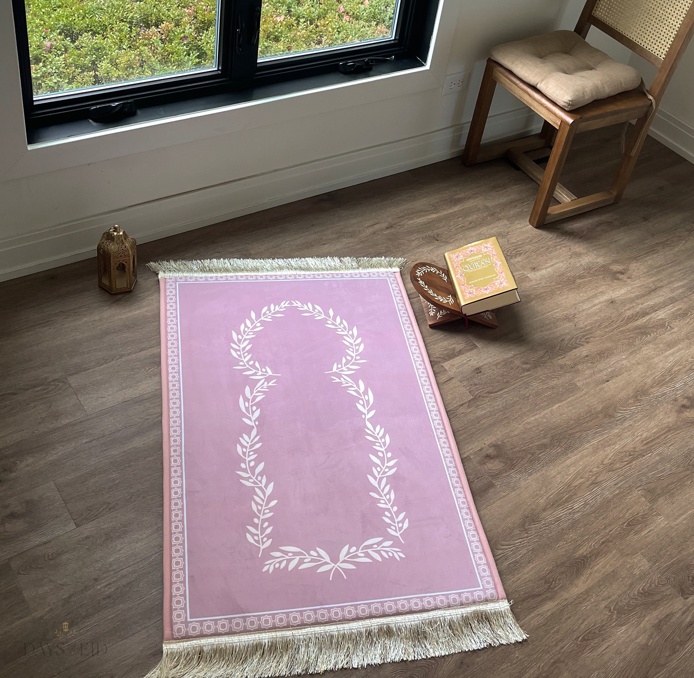 A pink and white prayer rug on a wooden floor